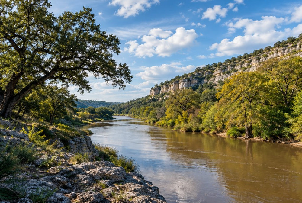 A slow Central Texas river with limestone bluffs and live oaks under a big sky